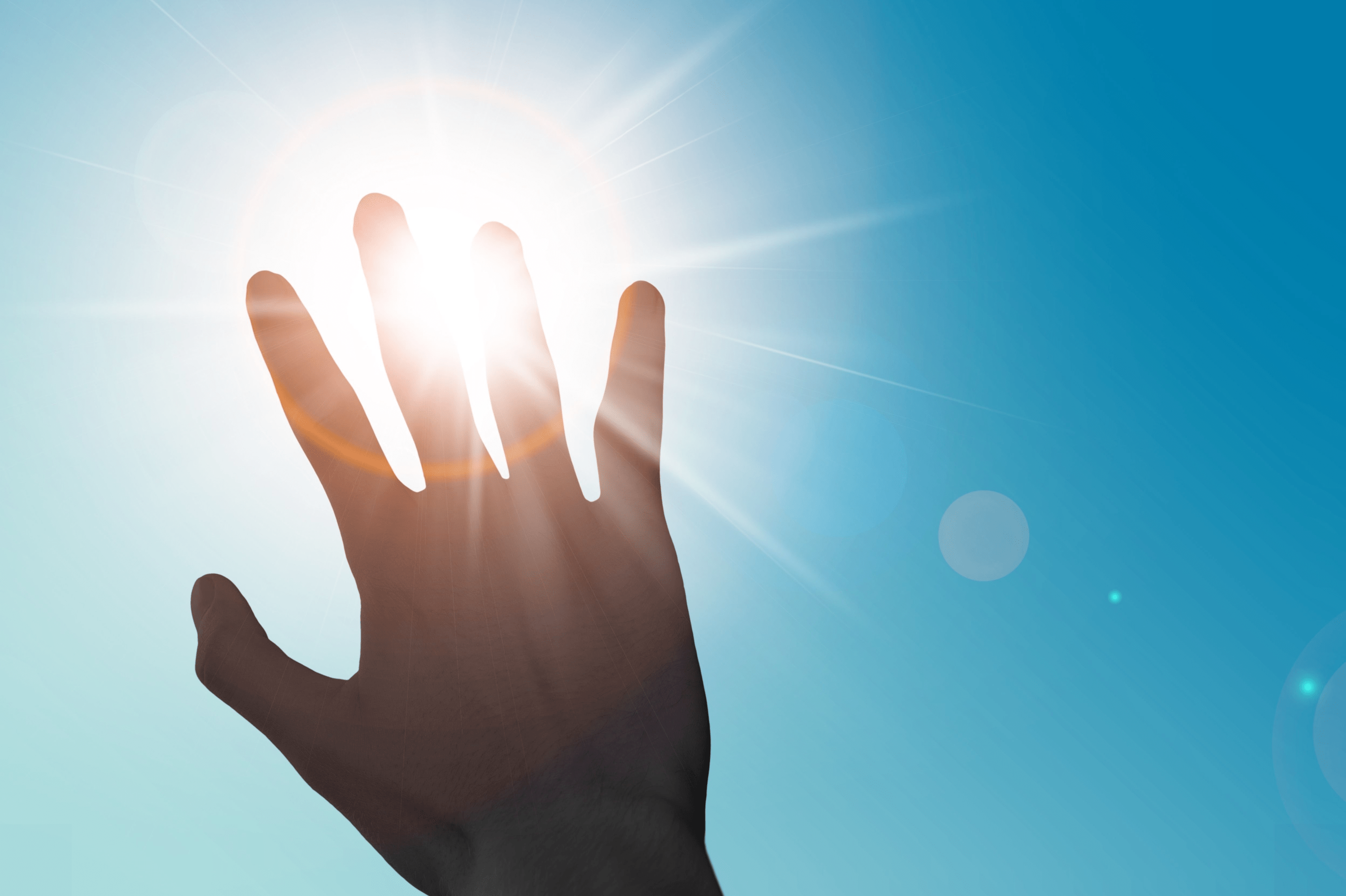 Eine Hand schirmt die Sonne vor blauem Himmel ab. Dieses Bild symbolisiert UV Schutz.